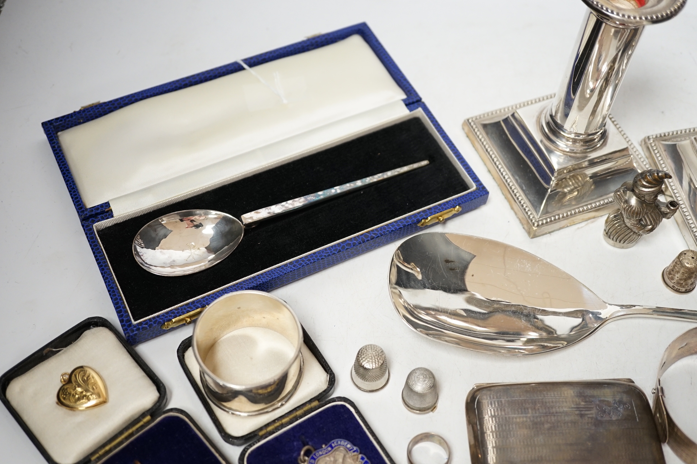 Sundry small silver including a cased preserve spoon, by Albert Edward Jones, a pair of mounted dwarf candlesticks, serving spoon, thimbles, napkin ring etc.